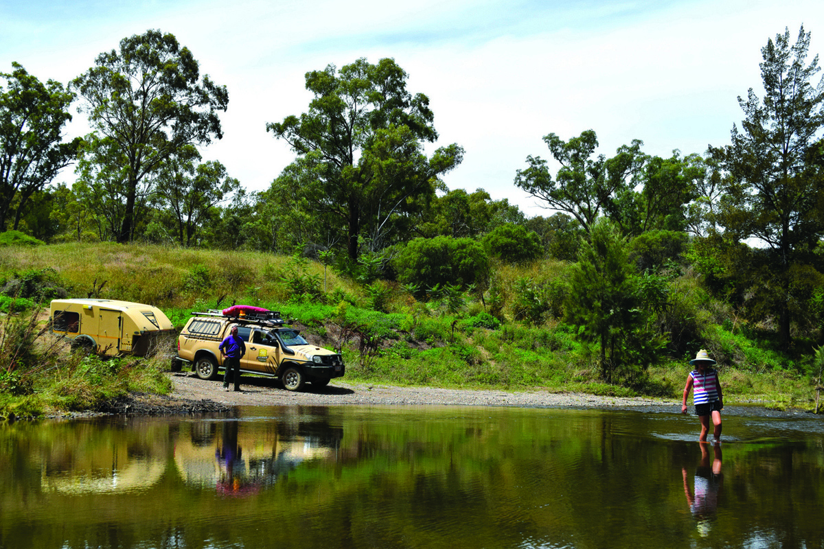 A person is walking across the river ahead of the 4WD