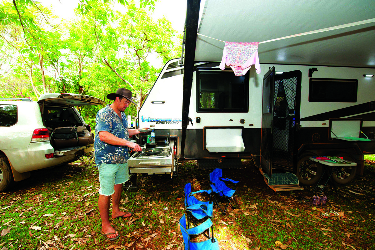 Man cooking in caravan outdoor kitchen