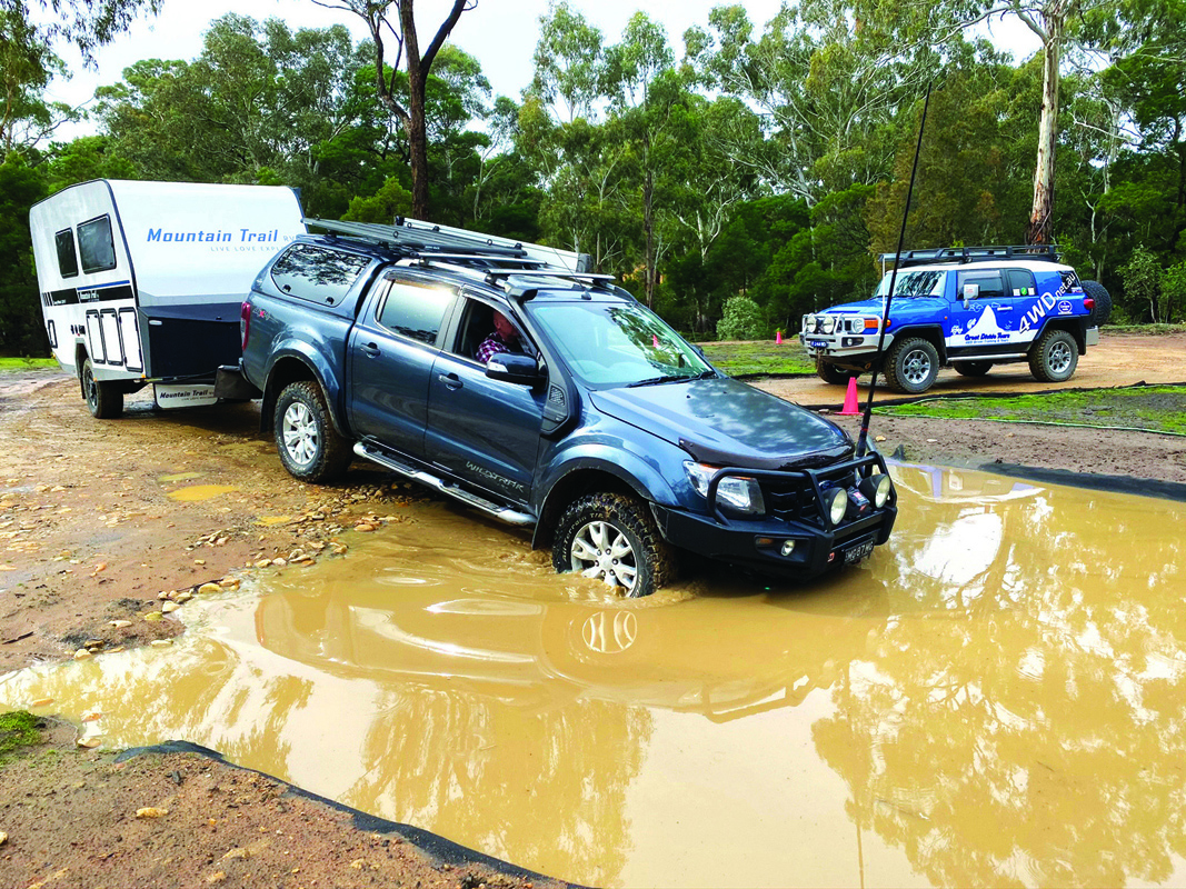 A 4WD towing a caravan is practicing a creek crossing during a 4WD course